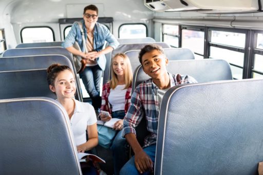 four teenagers sitting in a school bus waiting to go on a youth group trip
