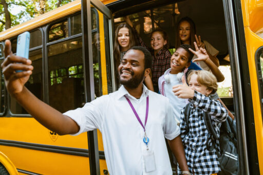 school bus driver taking a picture with a group of students on a school bus